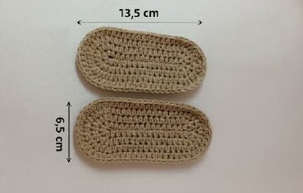 Two crochet baby shoe soles displayed side by side, measuring 13.5 cm in length and 6.5 cm in width, on a white background.